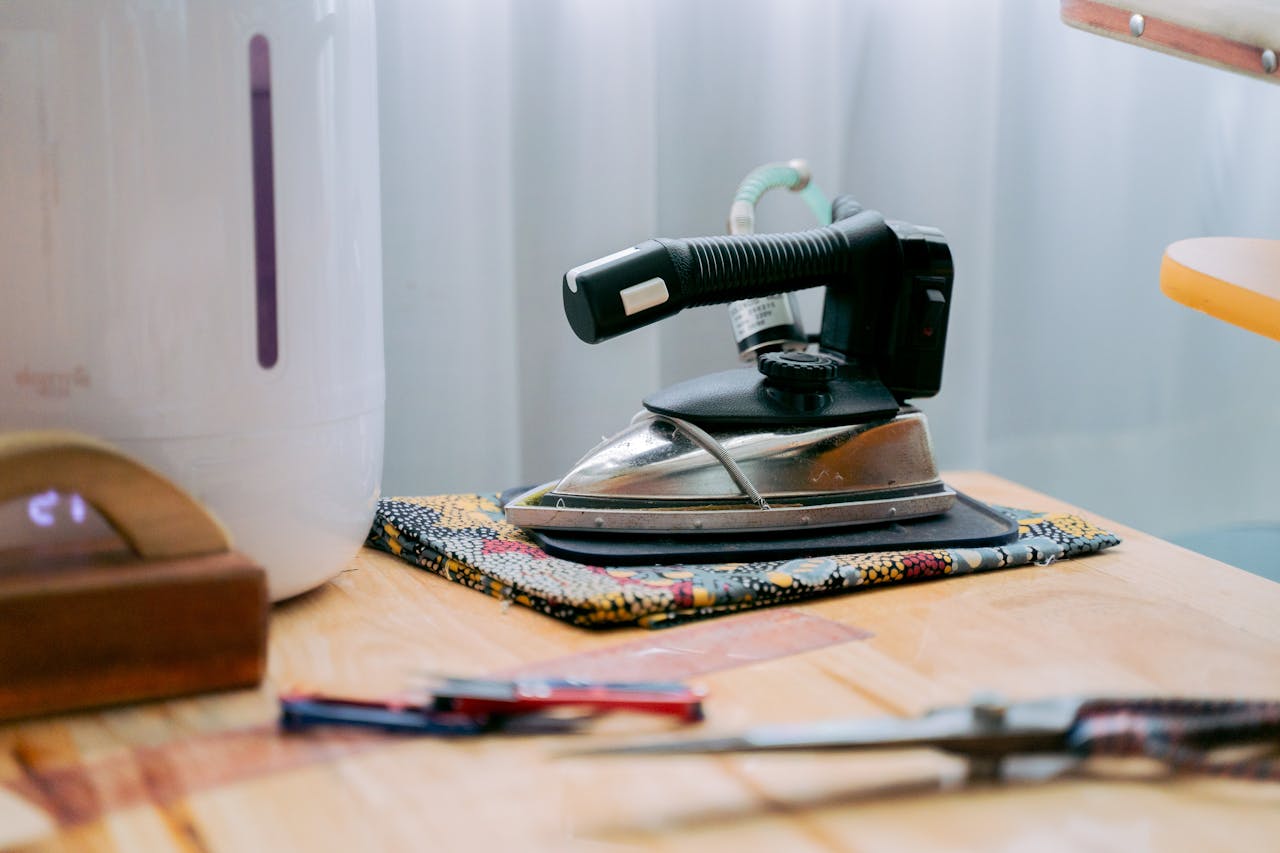 about-01 Retro iron on a wooden table beside other household items, evoking nostalgia.